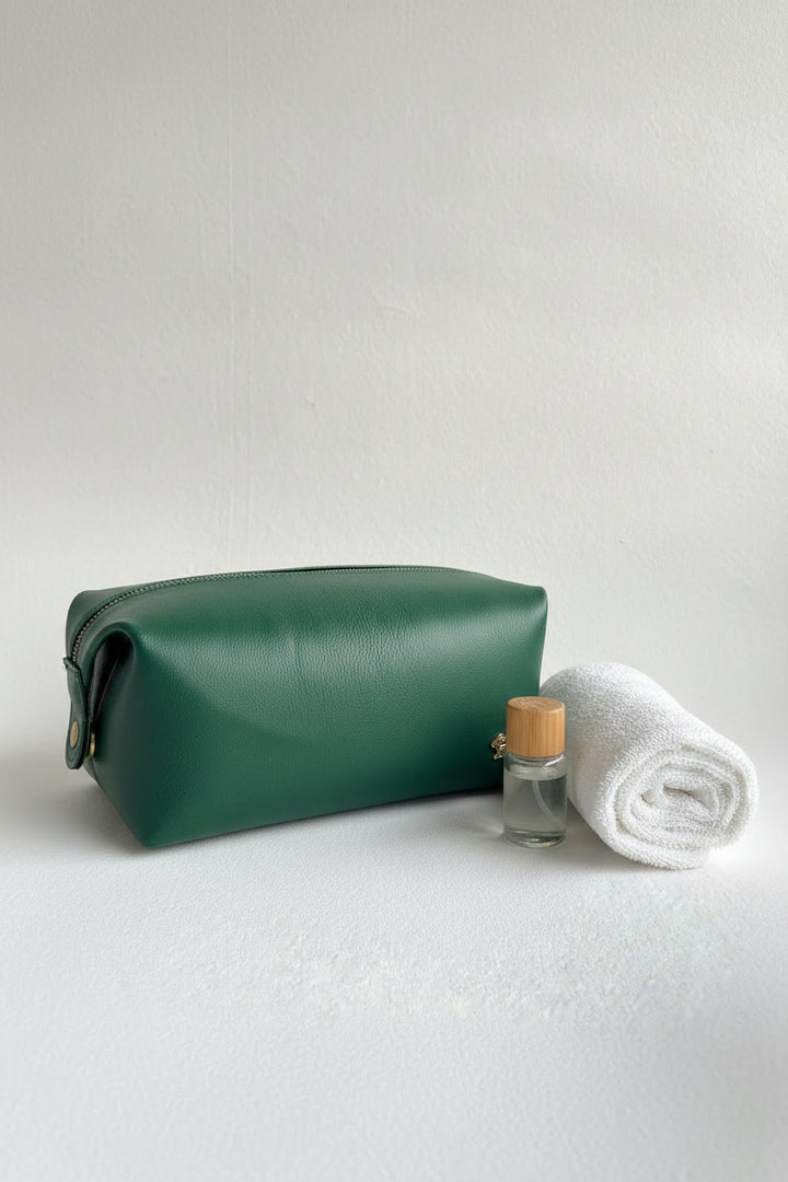 Green leather pouch with gold zipper and button on a white background